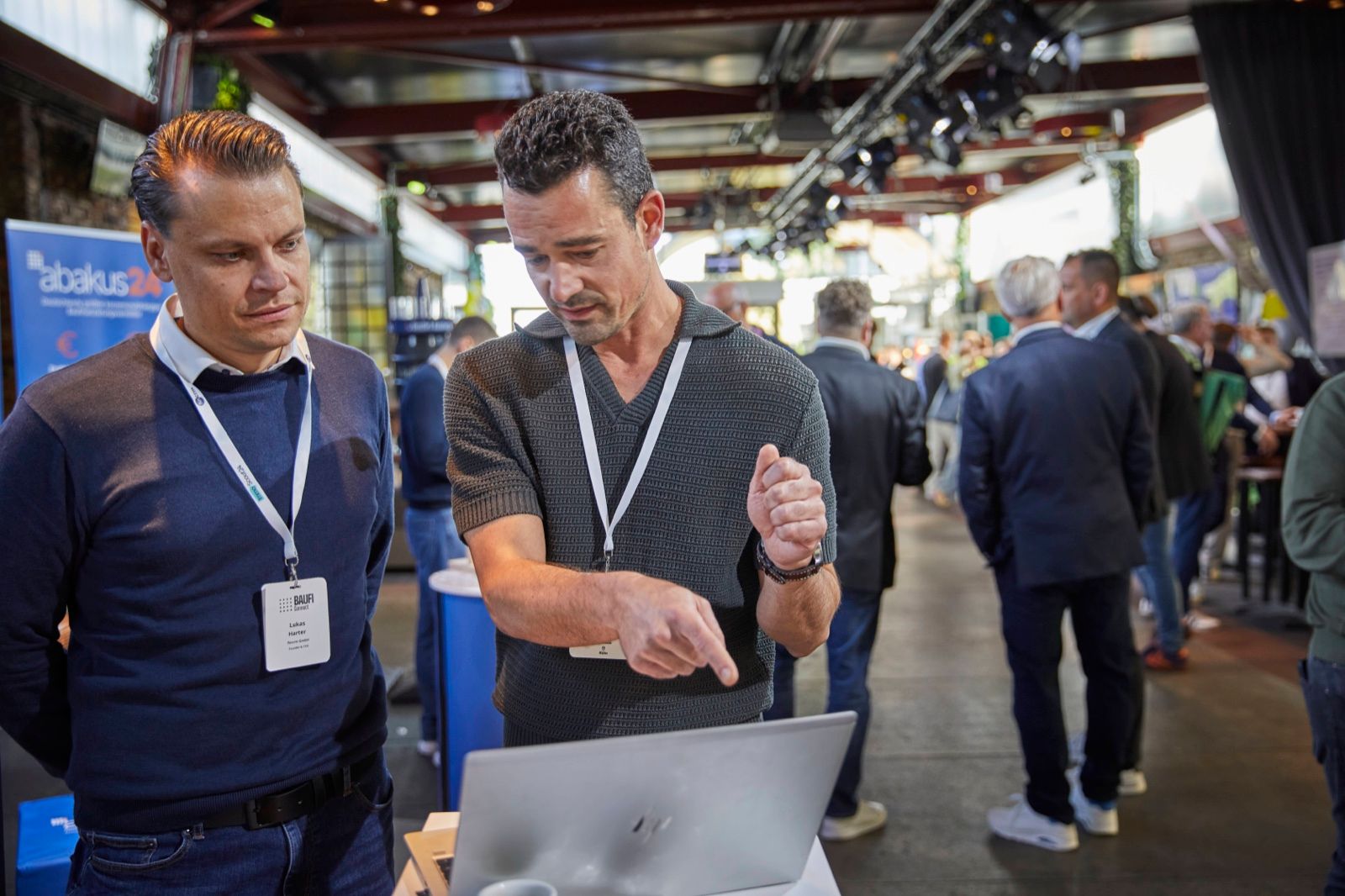 Gespräch am Laptop in der Expo der Baufi Connect 2026, im Hintergrund der volle Gang